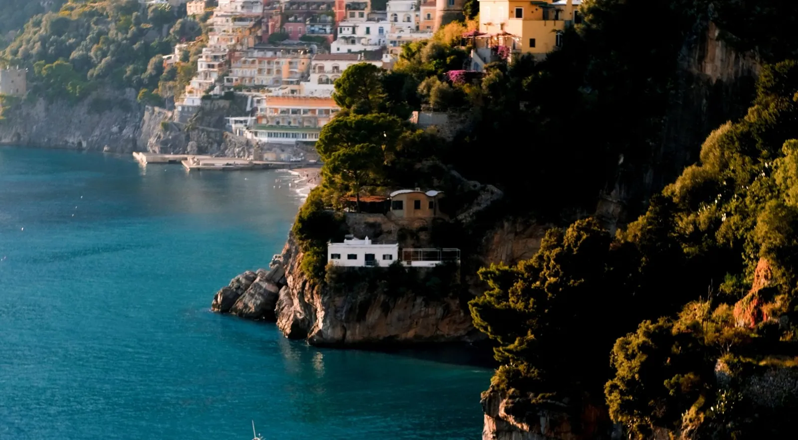 Villas on a rocky headland above deep blue water at golden hour