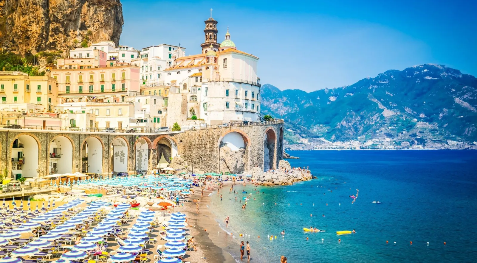 Atrani's beach and bell tower with mountains across the bay