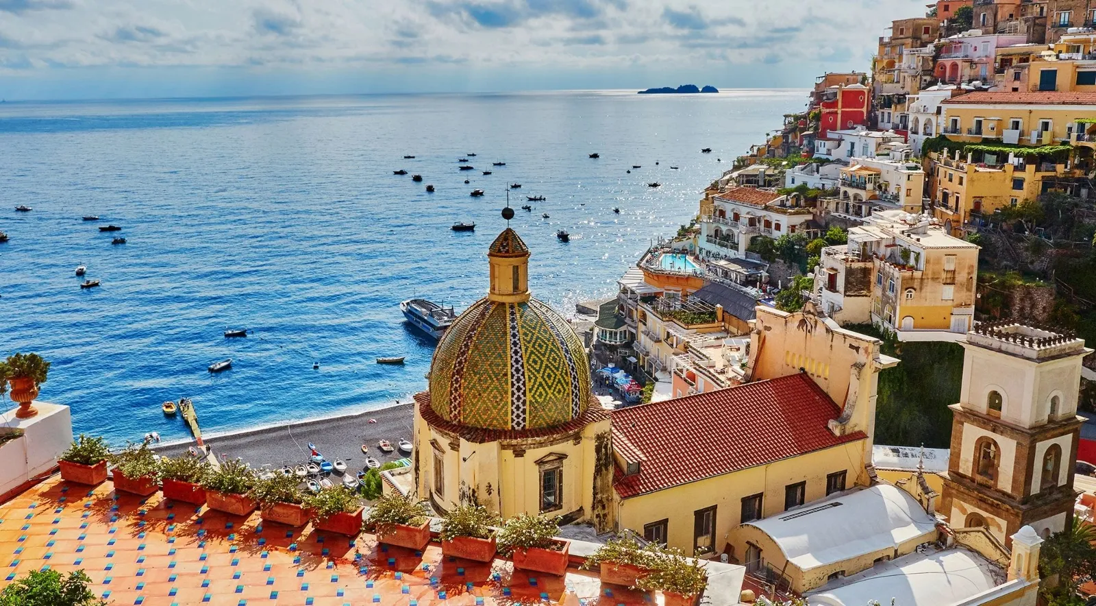 Positano's tiled church dome above the beach and the bay full of boats