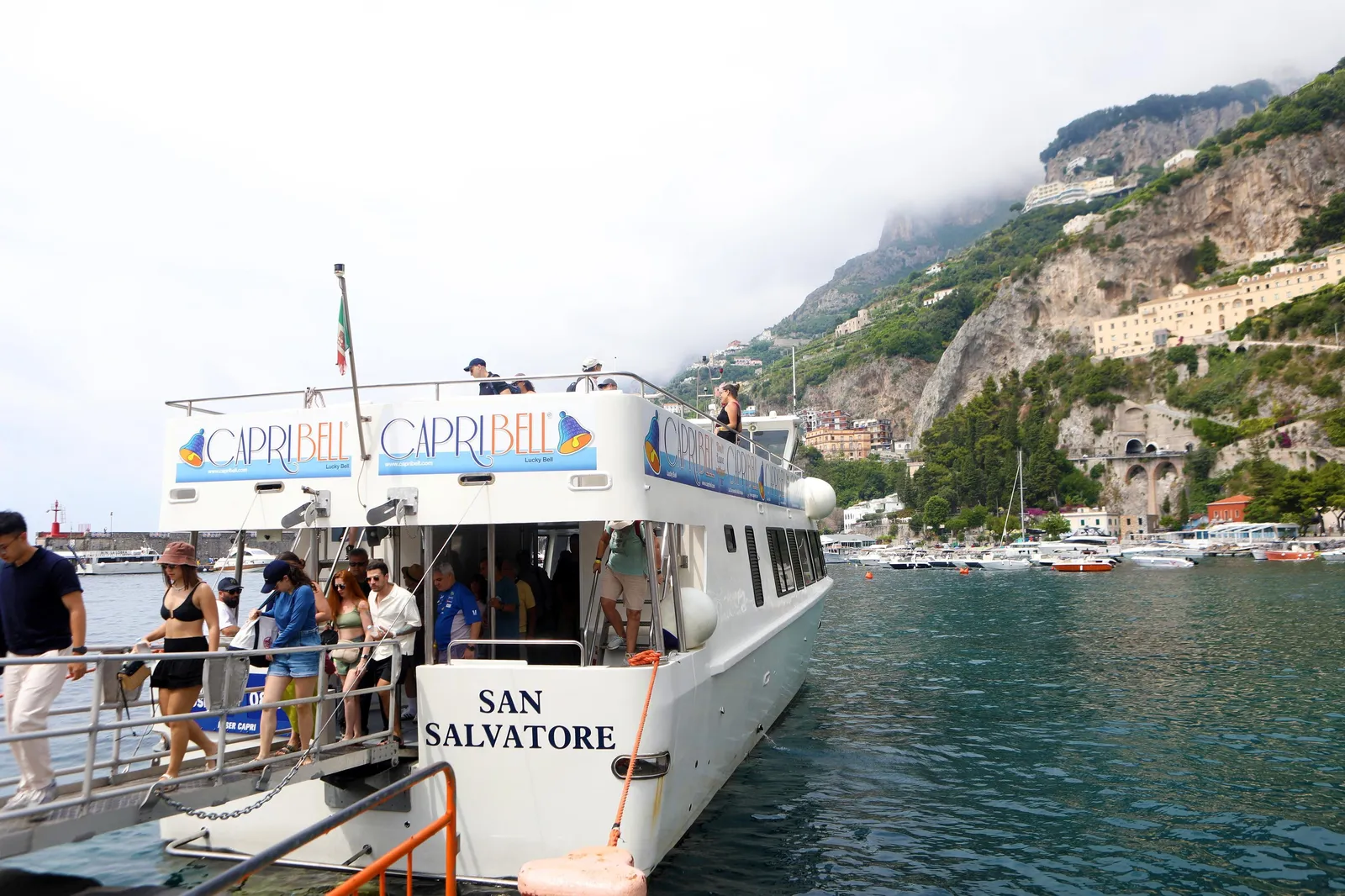 Passenger boat San Salvatore at a quay with people boarding and cliffs behind