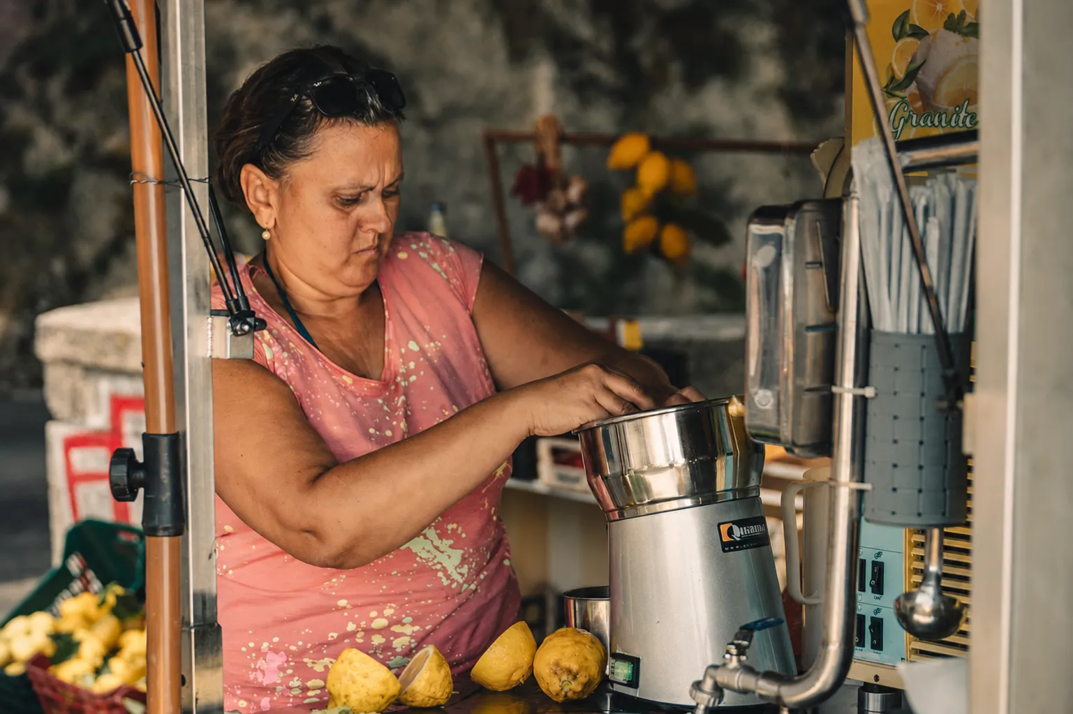 Woman squeezing lemons in a juicer at a roadside fruit stall