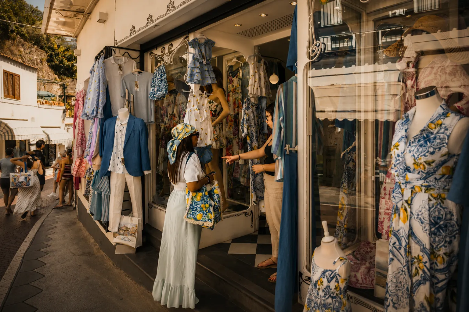 Clothing shop with dresses on mannequins and racks on a narrow village street