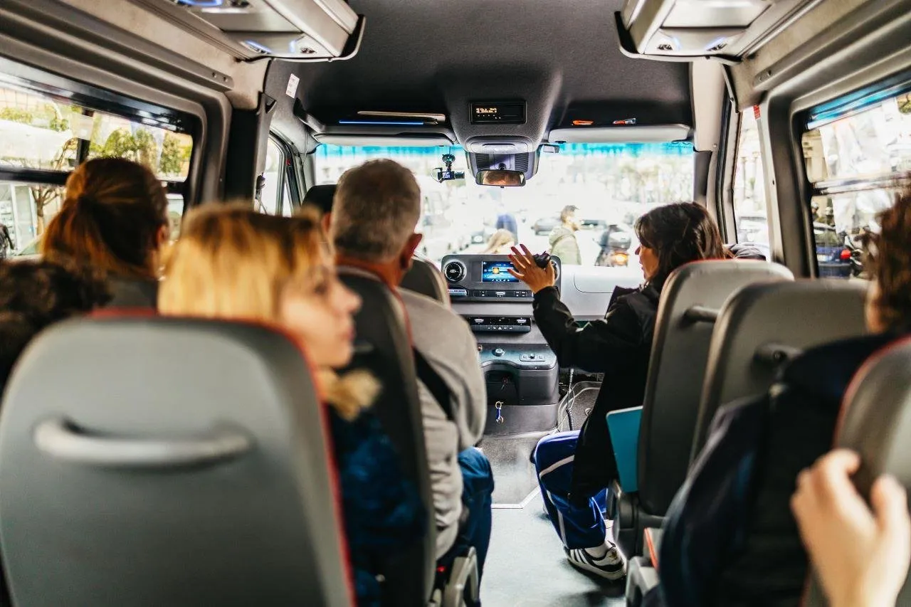 Passengers seated inside a minibus facing a road ahead