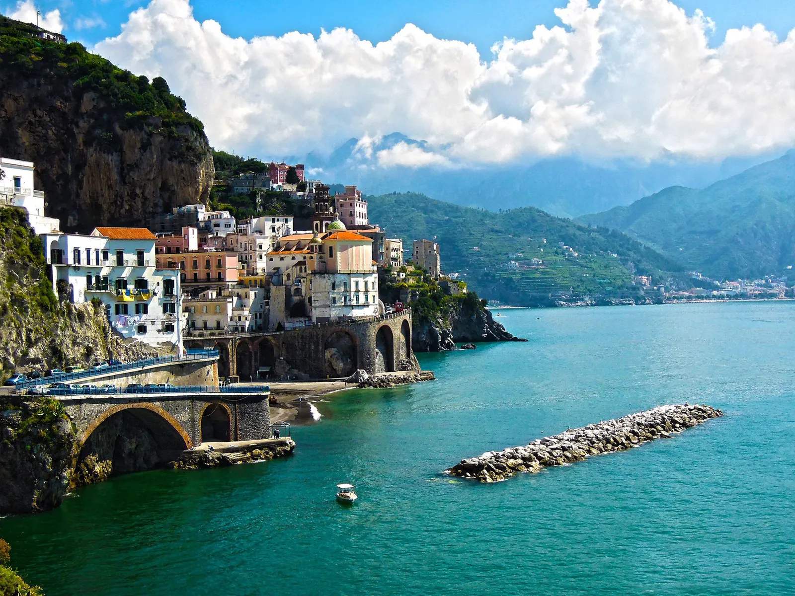 Amalfi's houses and arched buildings beside a breakwater and turquoise water