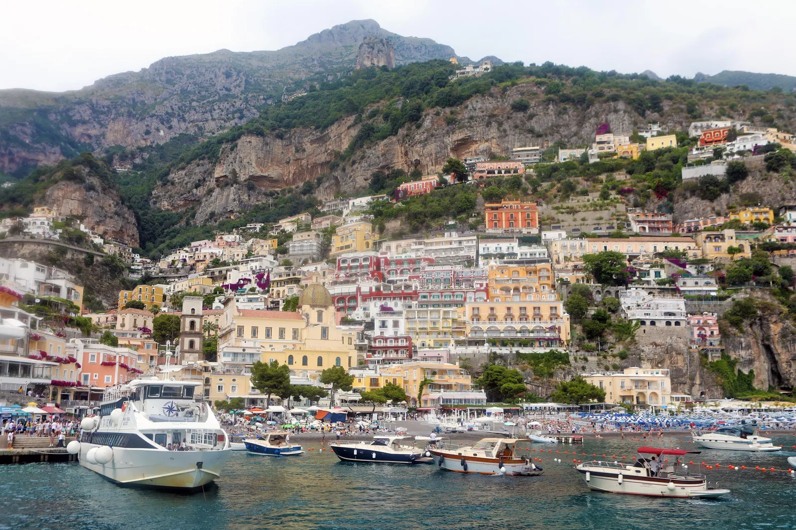 Positano's houses climbing a mountainside above a harbour full of boats