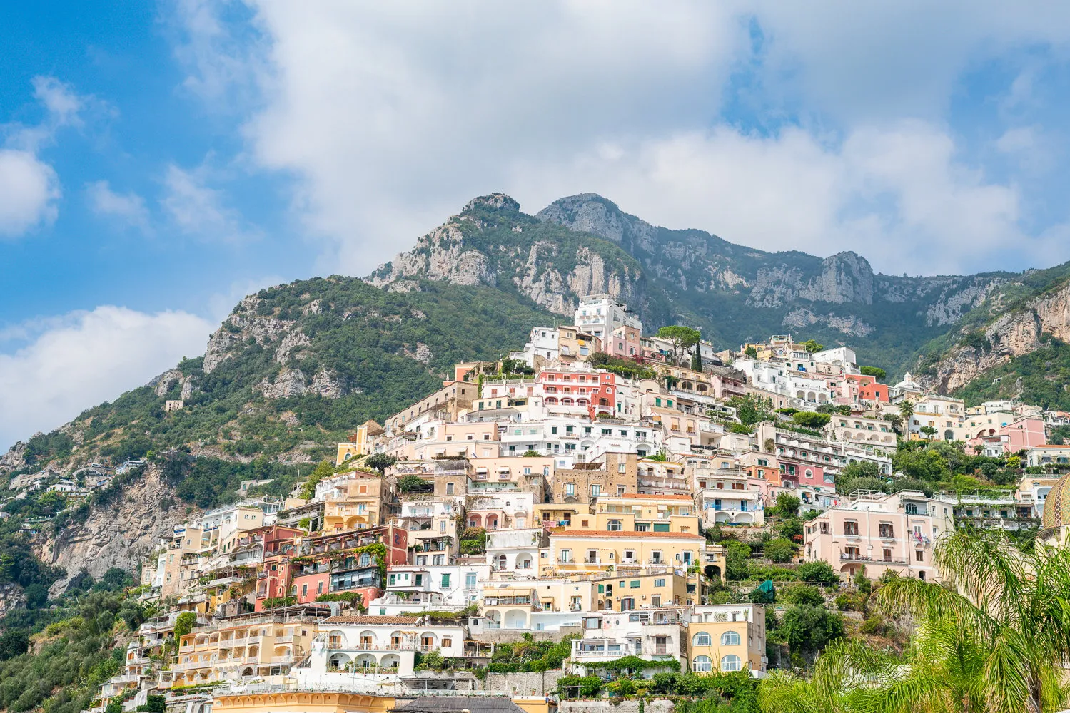 Pastel houses of a cliffside village climbing a steep green mountainside