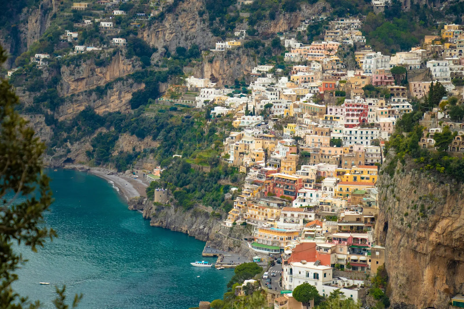 Steep hillside covered in colourful houses above a small bay with turquoise water