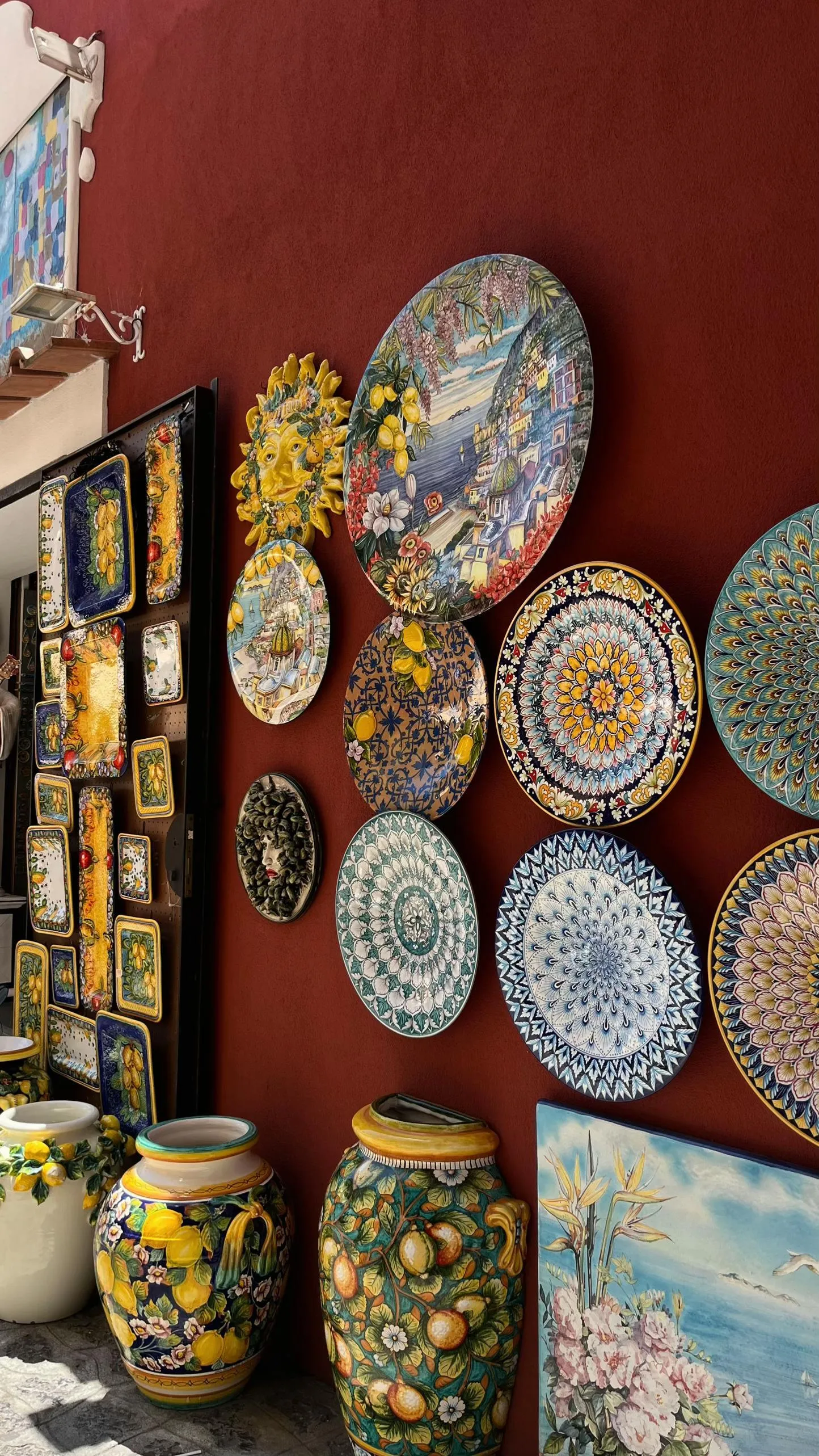 Painted ceramic plates and vases displayed on a red wall