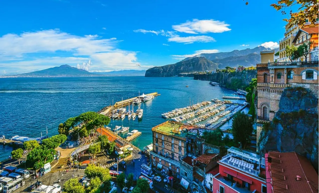 Sorrento's marina and cliffside buildings under a blue sky with a distant mountain