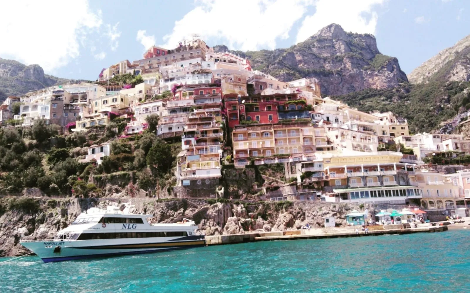 White passenger boat below Positano's pastel houses on a rocky slope