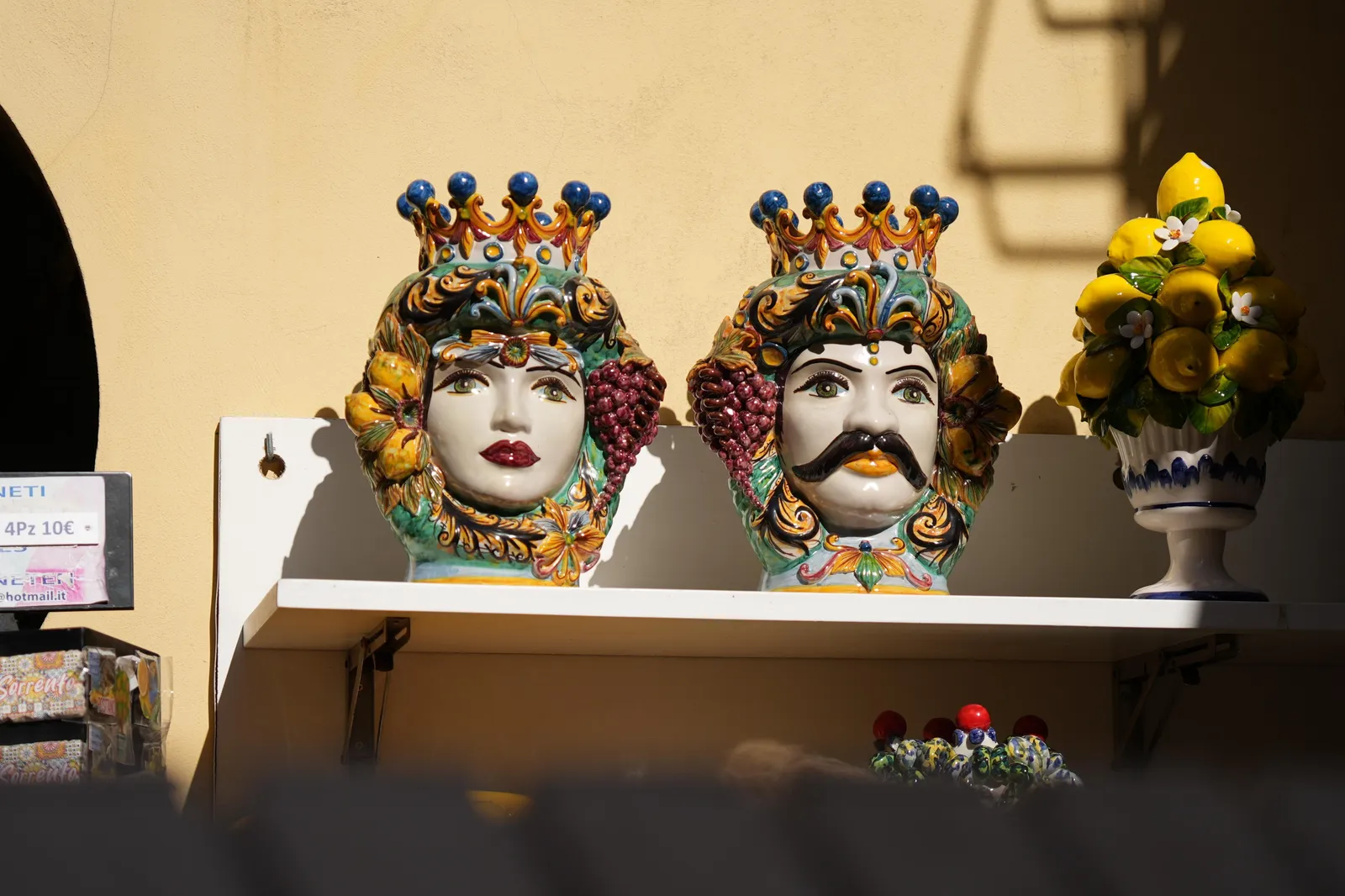 Painted ceramic Moor's head vases and a lemon-decorated pot on a shop shelf