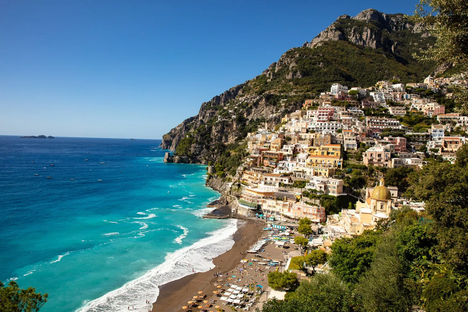 Positano's houses spilling down a rocky slope to a pebble beach and surf