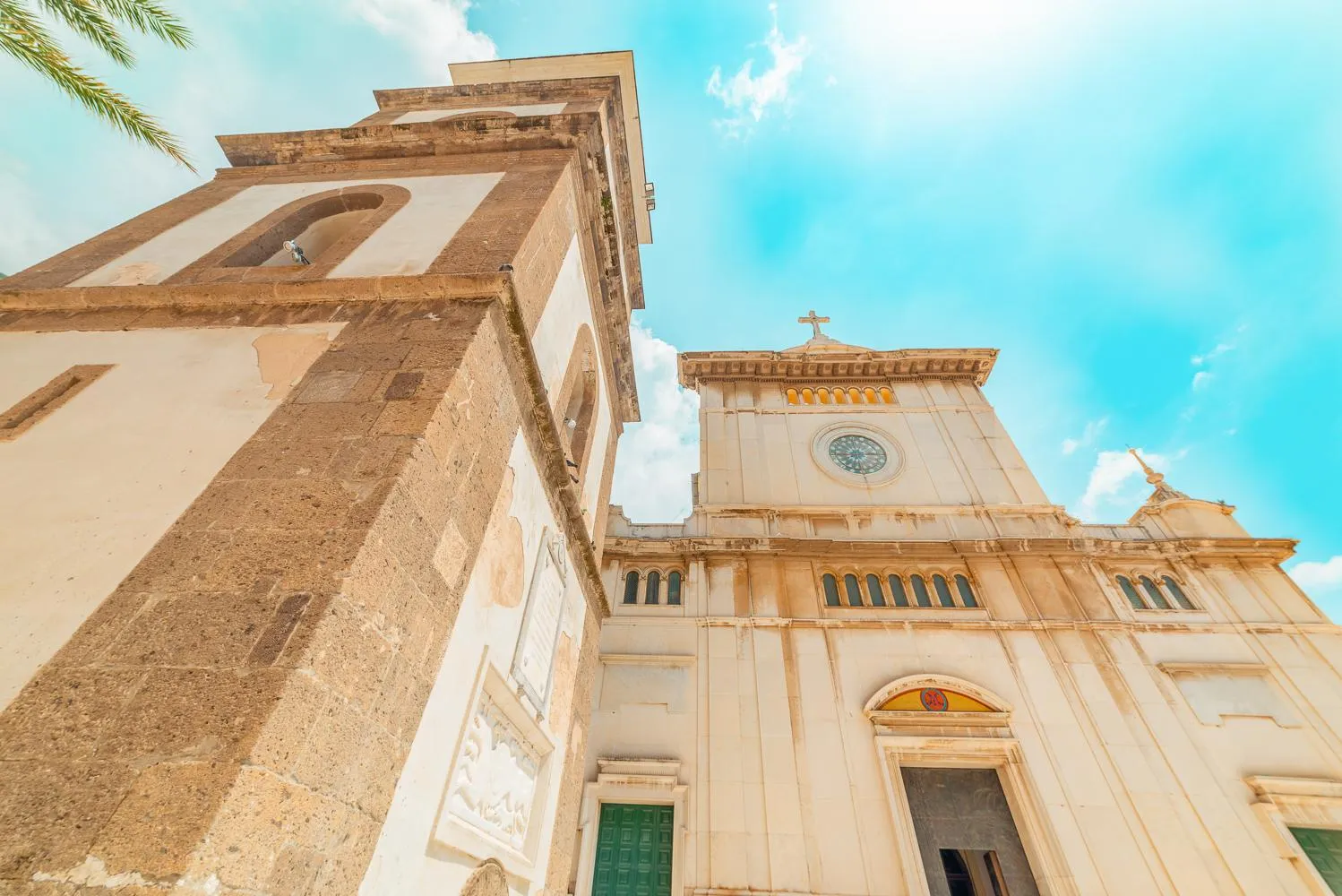 Church facade with a clock seen from below against a bright blue sky