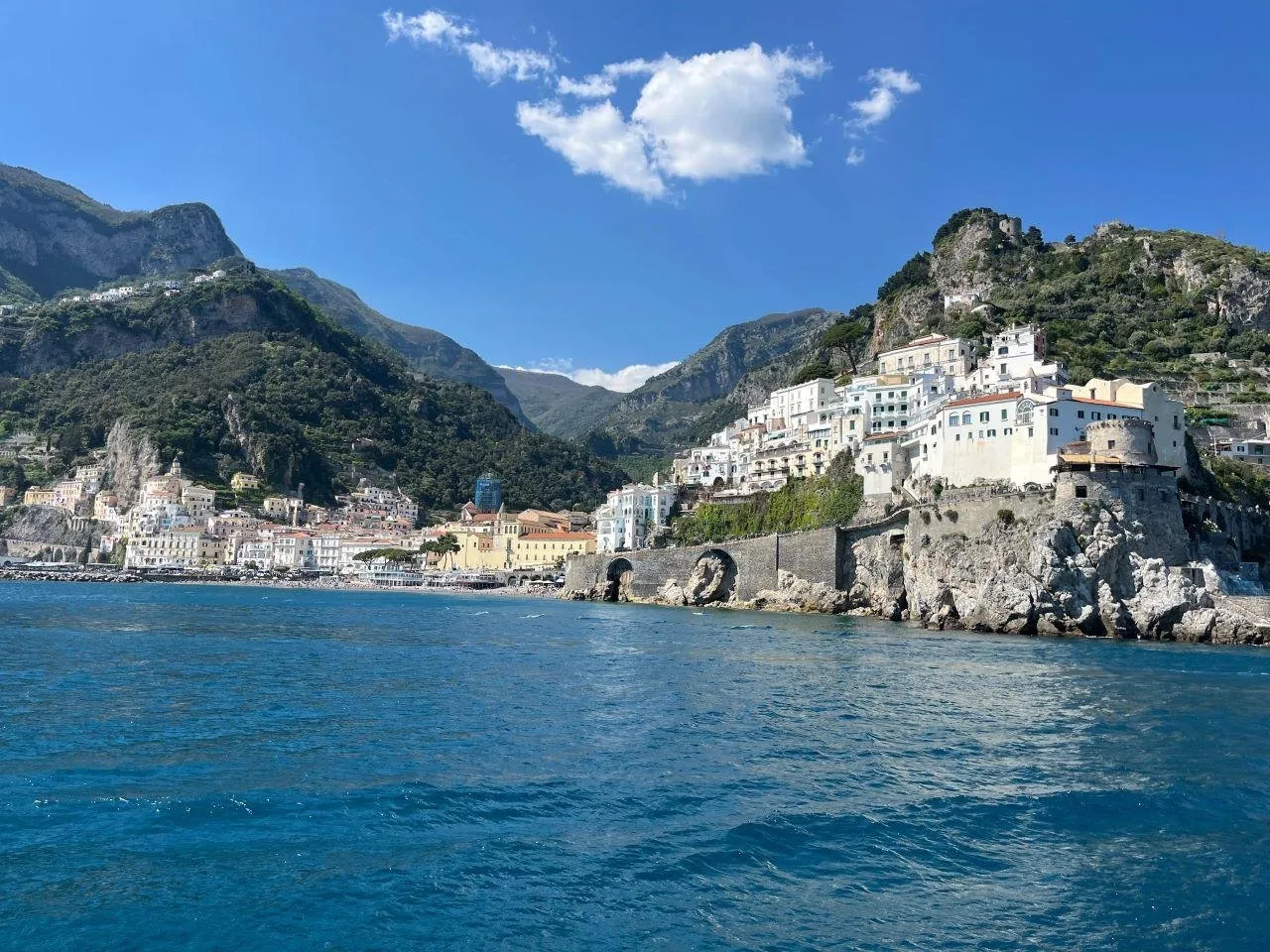 Amalfi's white houses on a rocky point above calm blue water