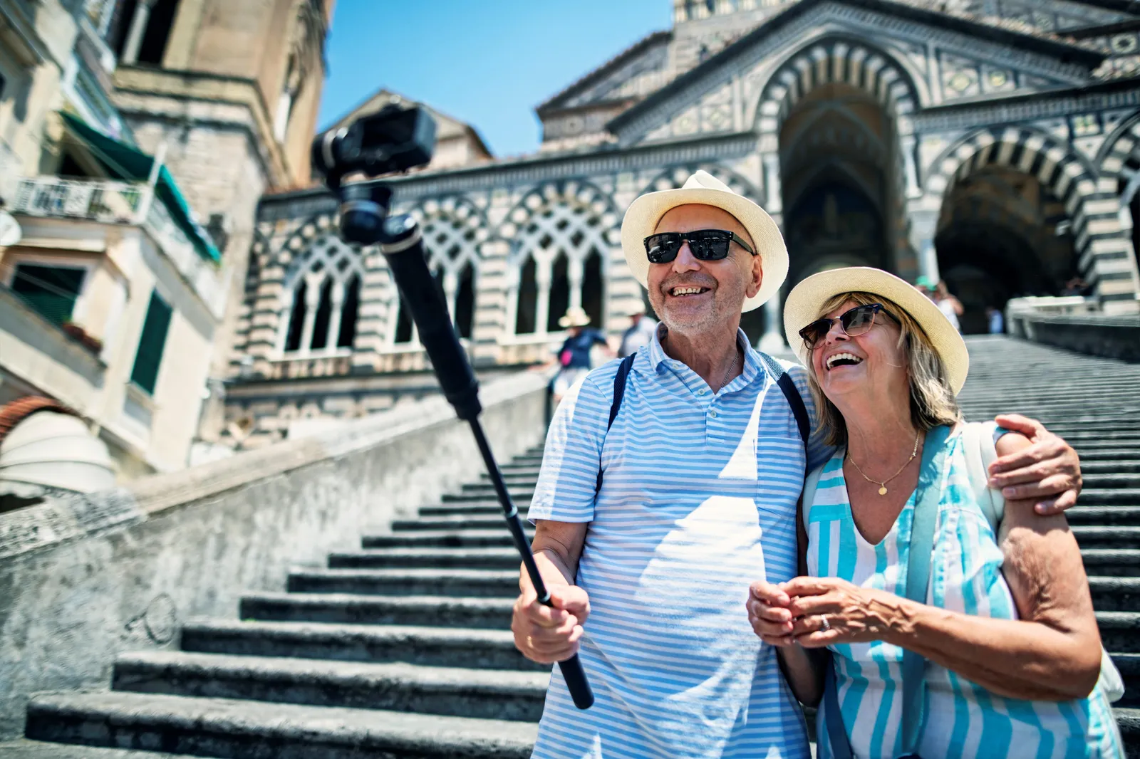 Couple with a selfie stick on the steps below Amalfi cathedral's striped facade
