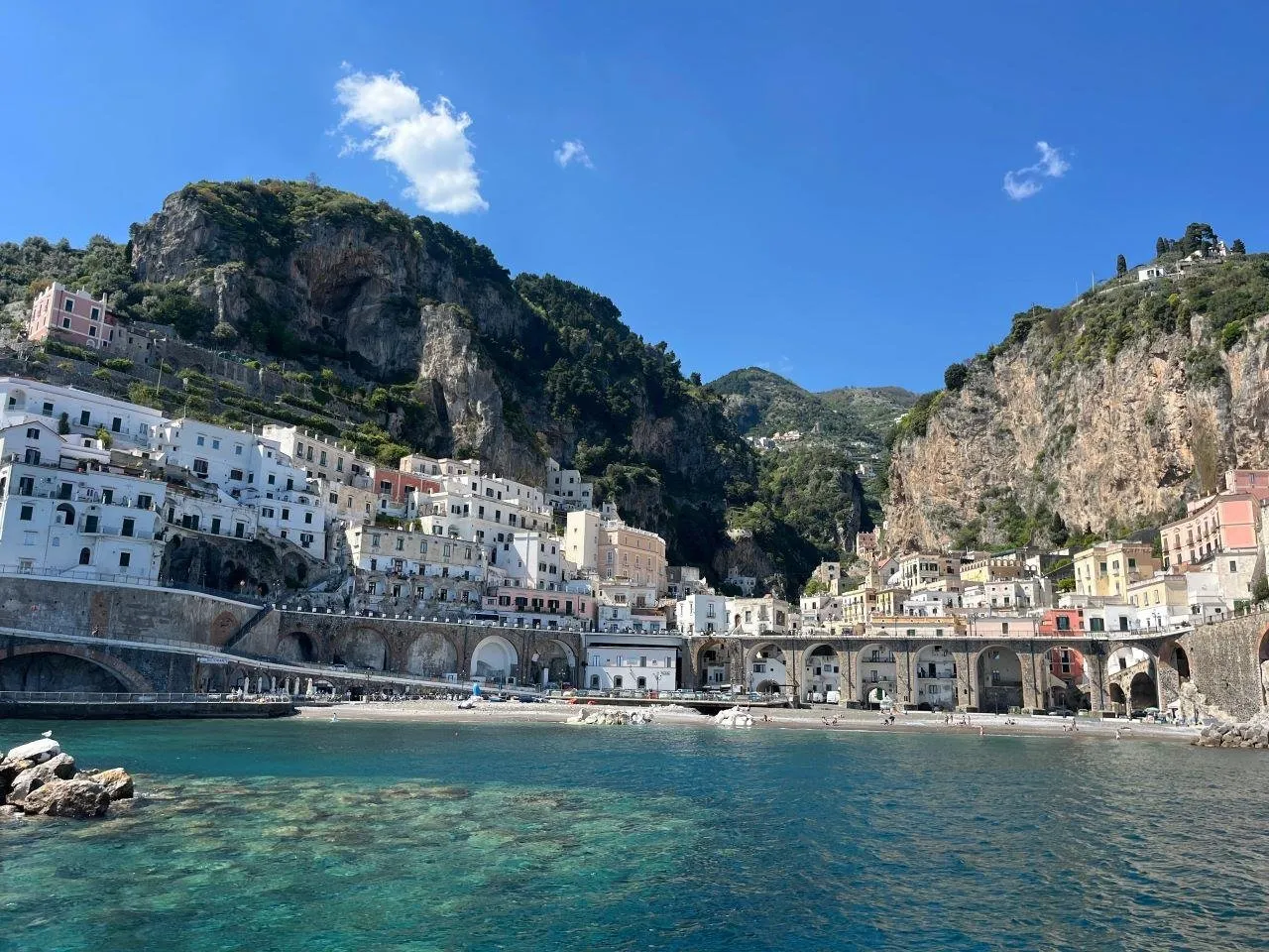 Arched seafront buildings at the foot of cliffs, above clear green water