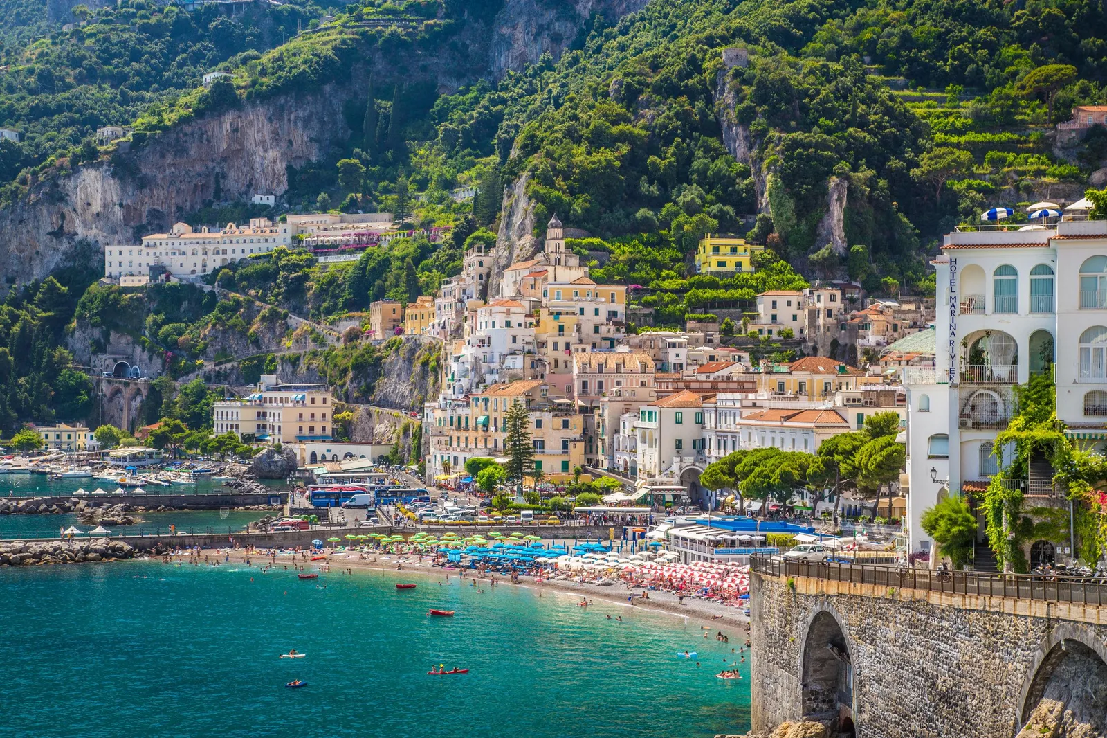Amalfi's beach, harbour and town below a steep green mountain